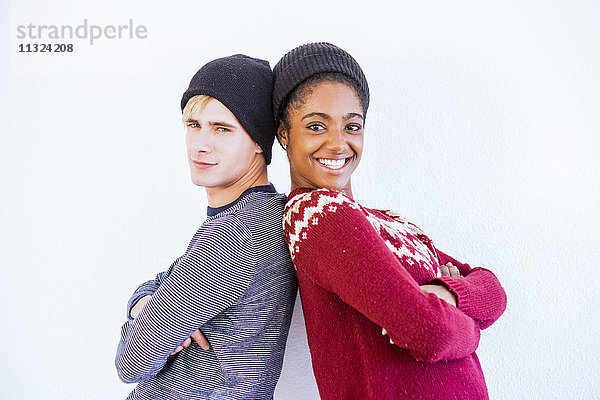 Portrait des jungen Paares Rücken an Rücken vor weißem Hintergrund