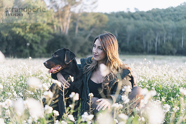 Junge Frau und ihr Hund im Blumenfeld