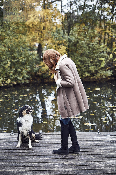 Frau mit ihrem Hund am Steg im Herbst