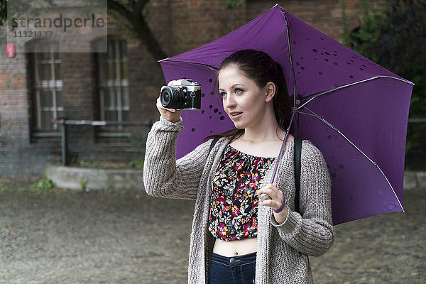 Junge Frau mit Kamera und Regenschirm-Ausgang