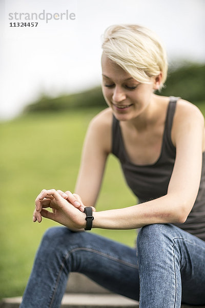 Lächelnde junge Frau überprüft ihre Smartwatch