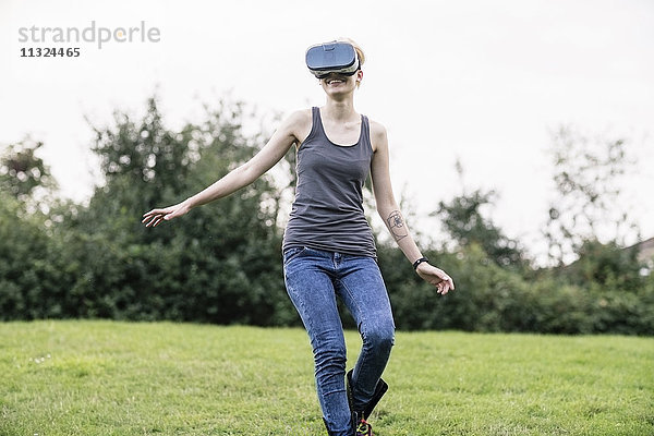 Lächelnde junge Frau mit Virtual Reality Brille im Freien