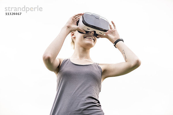 Lächelnde junge Frau mit Virtual Reality Brille im Freien