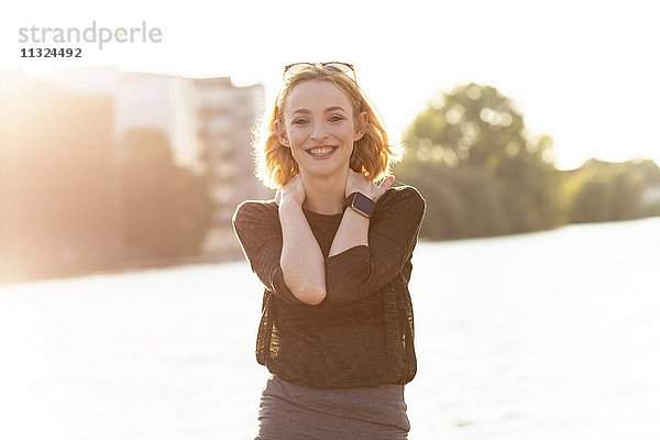 Porträt einer glücklichen jungen Frau mit Smartwatch im Gegenlicht