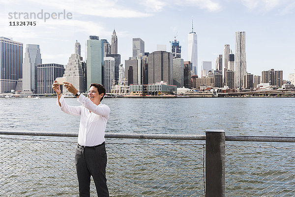 USA  Brooklyn  glückliche Geschäftsfrau vor der Skyline von Manhattan