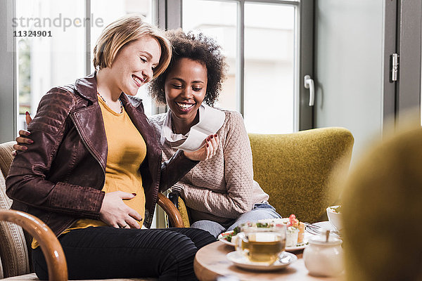 Schwangere junge Frau mit Freundin im Café