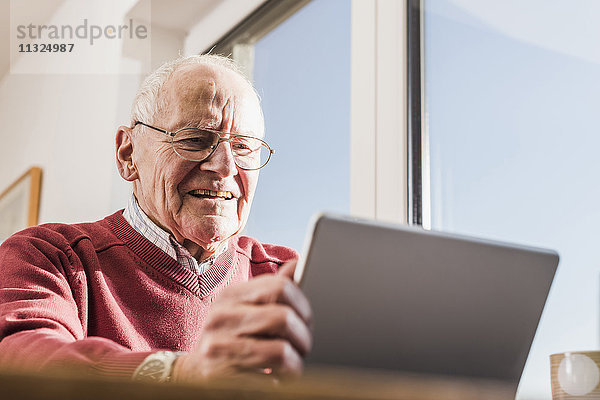 Senior Mann sitzt zu Hause  mit Laptop