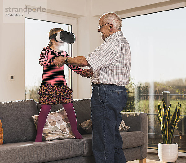 Großvater hält Enkelin  mit VR-Brille