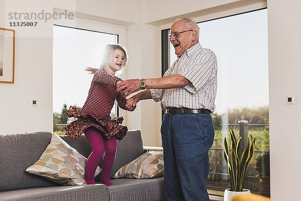 Großvater und Enkelin springen und tanzen auf der Couch