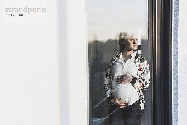 Schwangere Frau hinter der Fensterscheibe