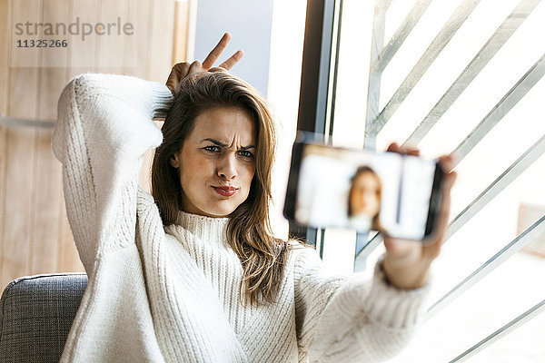 Verspielte junge Frau nimmt einen Selfie mit Handy