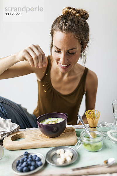 Frau bereitet Matcha Latte zu Hause vor