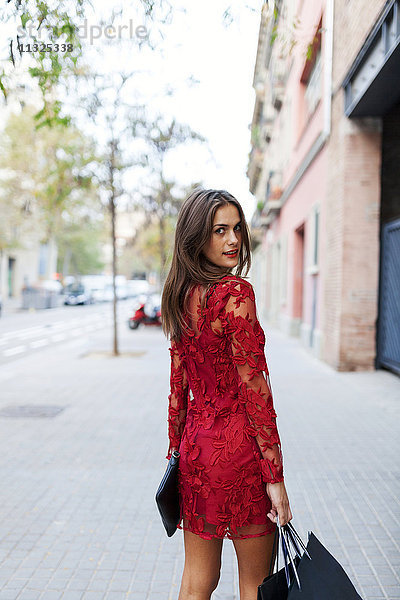 Schöne junge Frau in rotem Kleid mit Einkaufstaschen