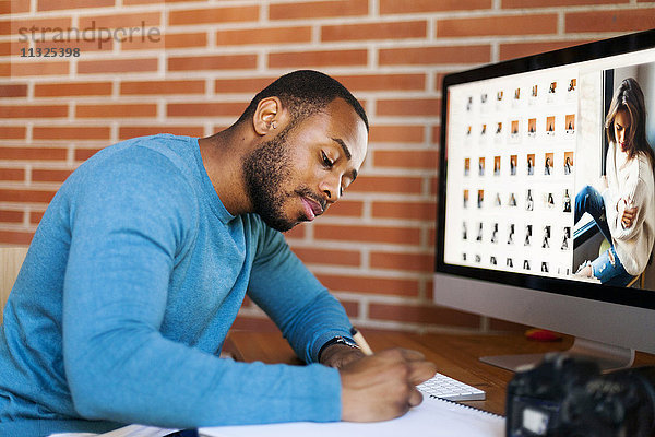 Junge Fotografin bearbeitet Bilder am Schreibtisch