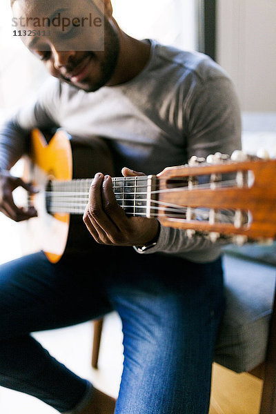 Junger Mann zu Hause beim Gitarrespielen