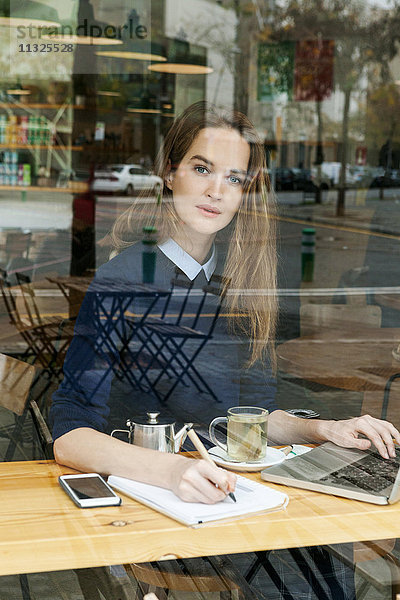 Junge Frau mit Laptop und Tasse Tee im Café