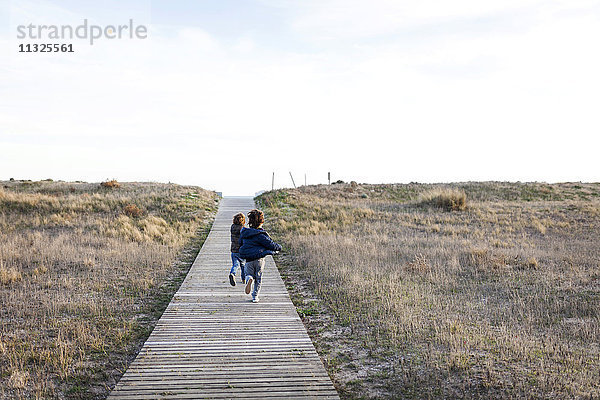 Kinder laufen am Strand auf Strandpromenade