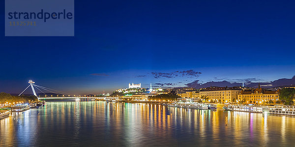 Slowakei  Bratislava  Blick auf beleuchtete Burg und Flusskreuzfahrtschiffe auf der Donau bei Nacht im Vordergrund