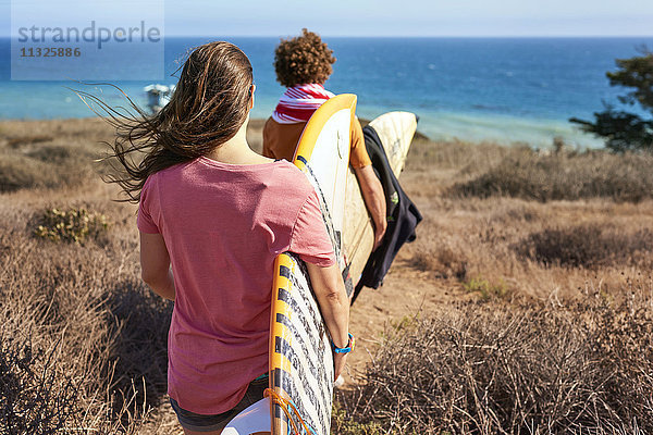 Paar mit Surfbrettern an der Küste