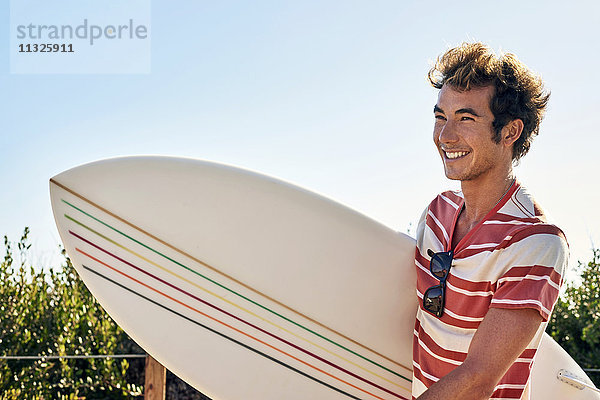 Lächelnder junger Mann mit Surfbrett