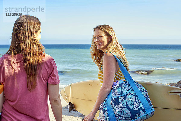 Zwei glückliche Frauen mit Surfbrettern am Strand