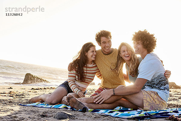 Glückliche Freunde sitzen am Strand