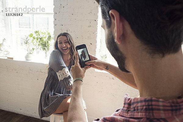 Fröhliche junge Frau posiert für eine Handy-Aufnahme