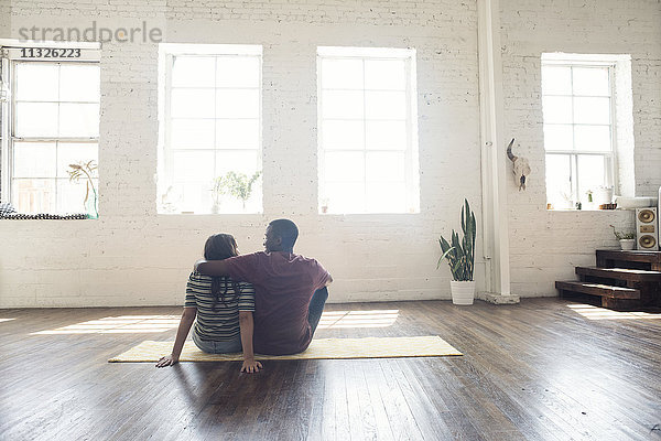 Junges Paar auf Teppich in einem Loft sitzend