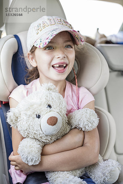 Mädchen im Auto sitzend  Teddybär haltend