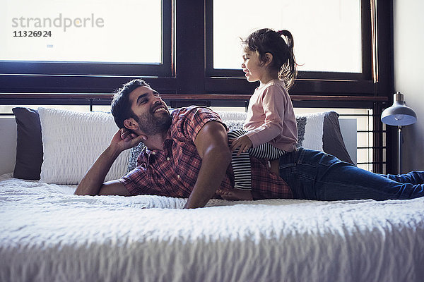 Vater und Tochter spielen auf dem Bett