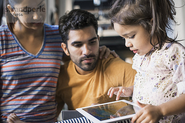Mutter und Vater beobachten Tochter mit digitalem Tablett