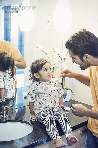 Vater und Tochter im Bad beim Zähneputzen