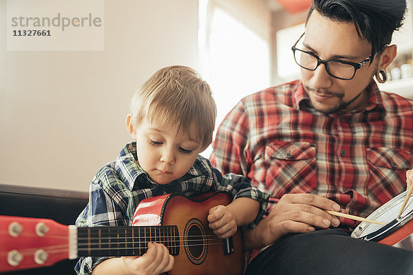 Vater und Sohn spielen Spielzeugmusikinstrumente