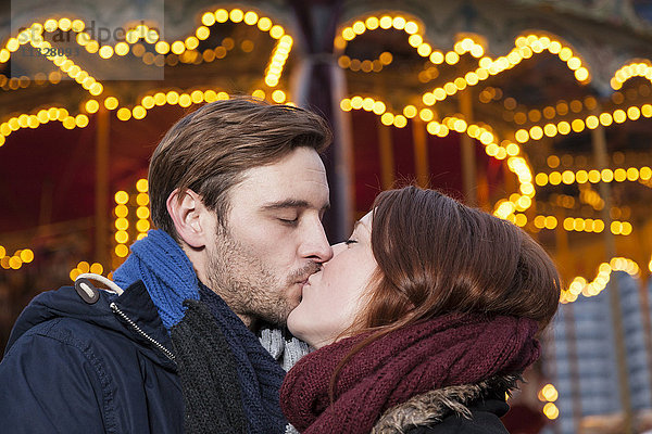 Paar küsst sich auf dem Weihnachtsmarkt