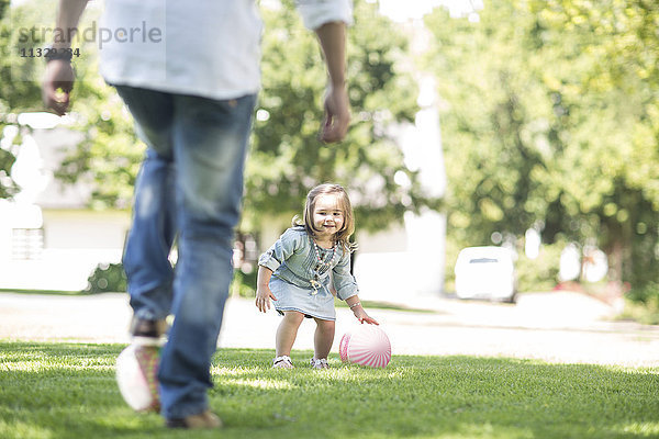 Vater spielt Ball im Garten mit Tochter