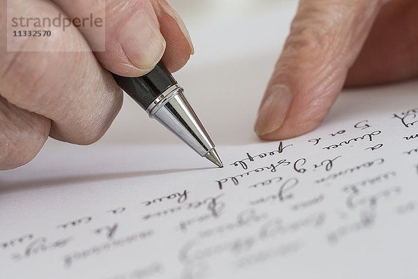 Ältere Frau schreibt auf ein weißes Blatt.