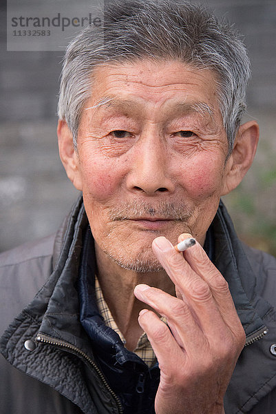 Asien China Peking  älterer Mann beim Rauchen