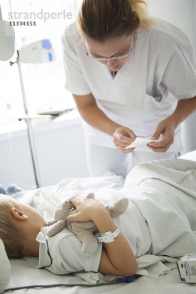 Reportage über die pädiatrische Abteilung eines Krankenhauses in Haute-Savoie  Frankreich. Eine Krankenschwester klebt einem jungen Patienten vor einer Blutuntersuchung ein Anästhesiepflaster auf.