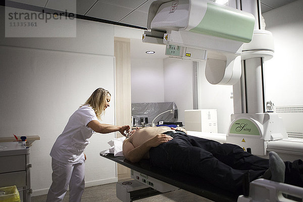 Reportage in einem radiologischen Zentrum in Haute-Savoie  Frankreich. Ein Techniker bereitet einen Patienten für eine Arthographie der Schulter vor.