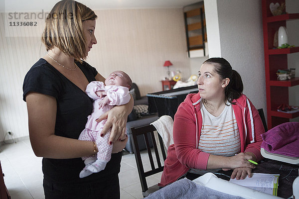Reportage über eine unabhängige Hebamme bei Hausbesuchen nach der Geburt. Die Hebamme füllt die Gesundheitsakte des Babys aus.