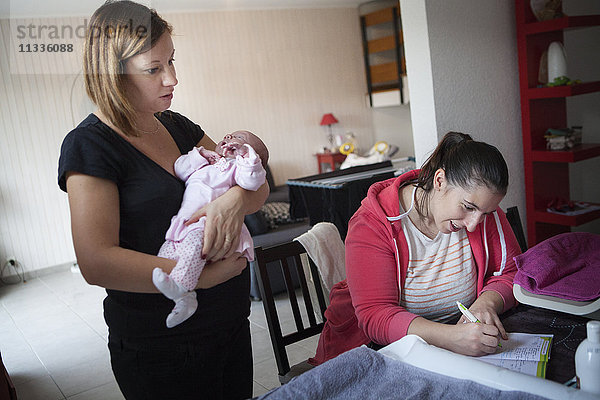 Reportage über eine unabhängige Hebamme bei Hausbesuchen nach der Geburt. Die Hebamme füllt die Gesundheitsakte des Babys aus.