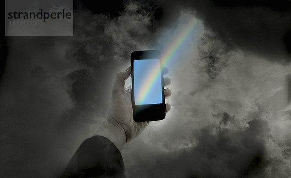 Das Ende des Regenbogens auf einem Smartphone in der Hand eines Mannes