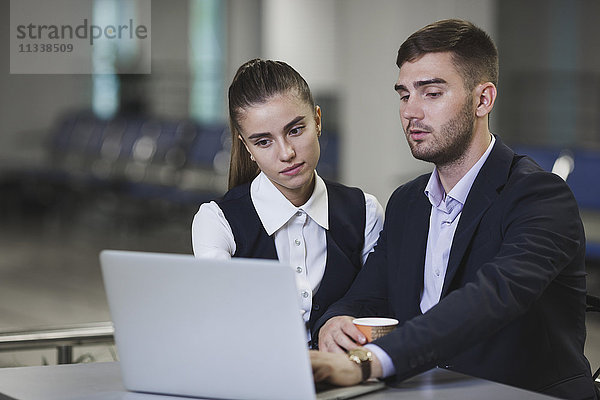 Junger Geschäftsmann und Geschäftsfrau mit Laptop am Tisch des Flughafens