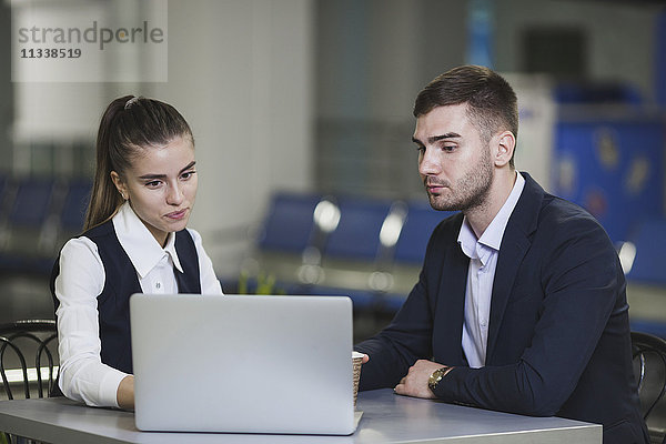 Junger Geschäftsmann und Geschäftsfrau mit Laptop am Flughafen