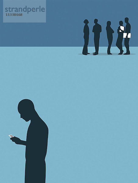 Mann benutzt ein Handy isoliert von einer Gruppe sich unterhaltender Menschen