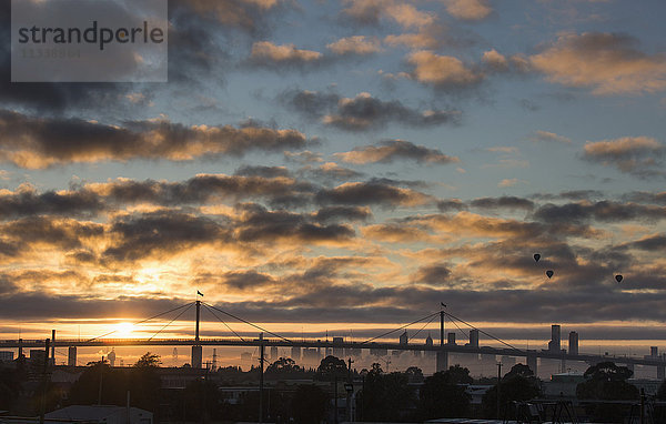 Blick auf Brücke und Skyline vor bewölktem Himmel bei Sonnenuntergang  Melbourne  Victoria  Australien