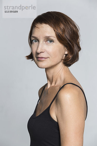 Seitenansicht Porträt einer selbstbewussten Frau vor grauem Hintergrund