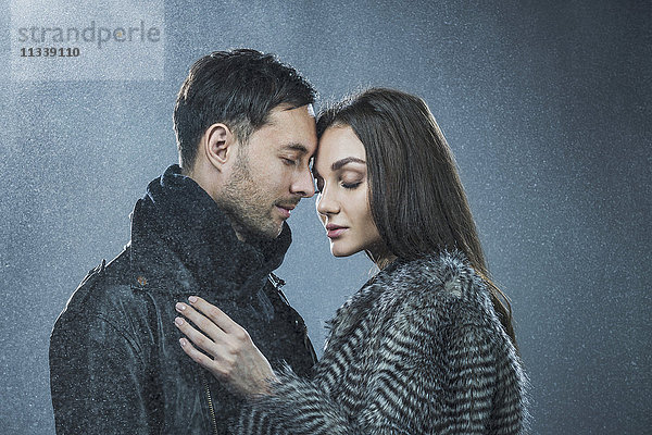 Romantisches Paar in warmer Kleidung vor grauem Hintergrund