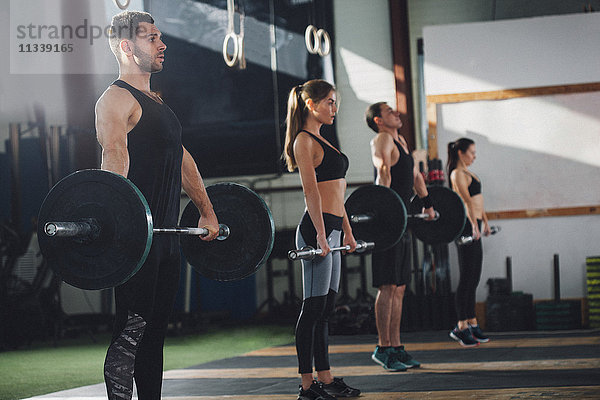 Seitenansicht der Athletinnen und Athleten beim Heben von Hanteln im Fitnessstudio