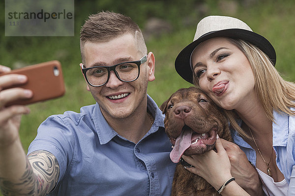 Ein Paar mit ihrem Shar-pei/Staffordshire Terrier im Park mit einem Selfie.
